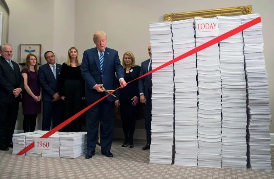 Trump uses gold scissors to cut a red tape